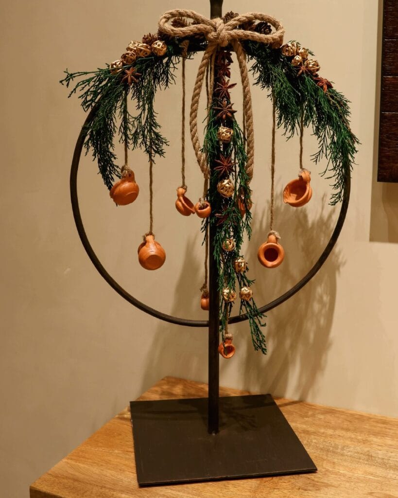 Wrought-iron hoop with a garland of green foliage, rope and clay ornaments.